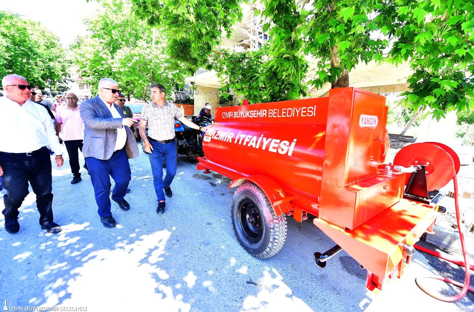 Yukarıkızılca’da İzmir İtfaiyesi yazılı kırmızı yangın tankeri ile ekipmanı inceleyen katılımcılar